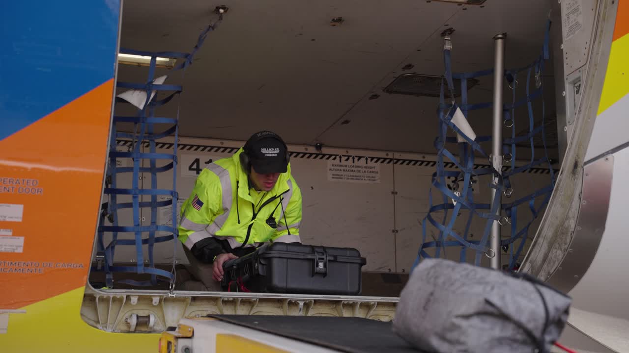 Airport worker unloading luggage off of plane