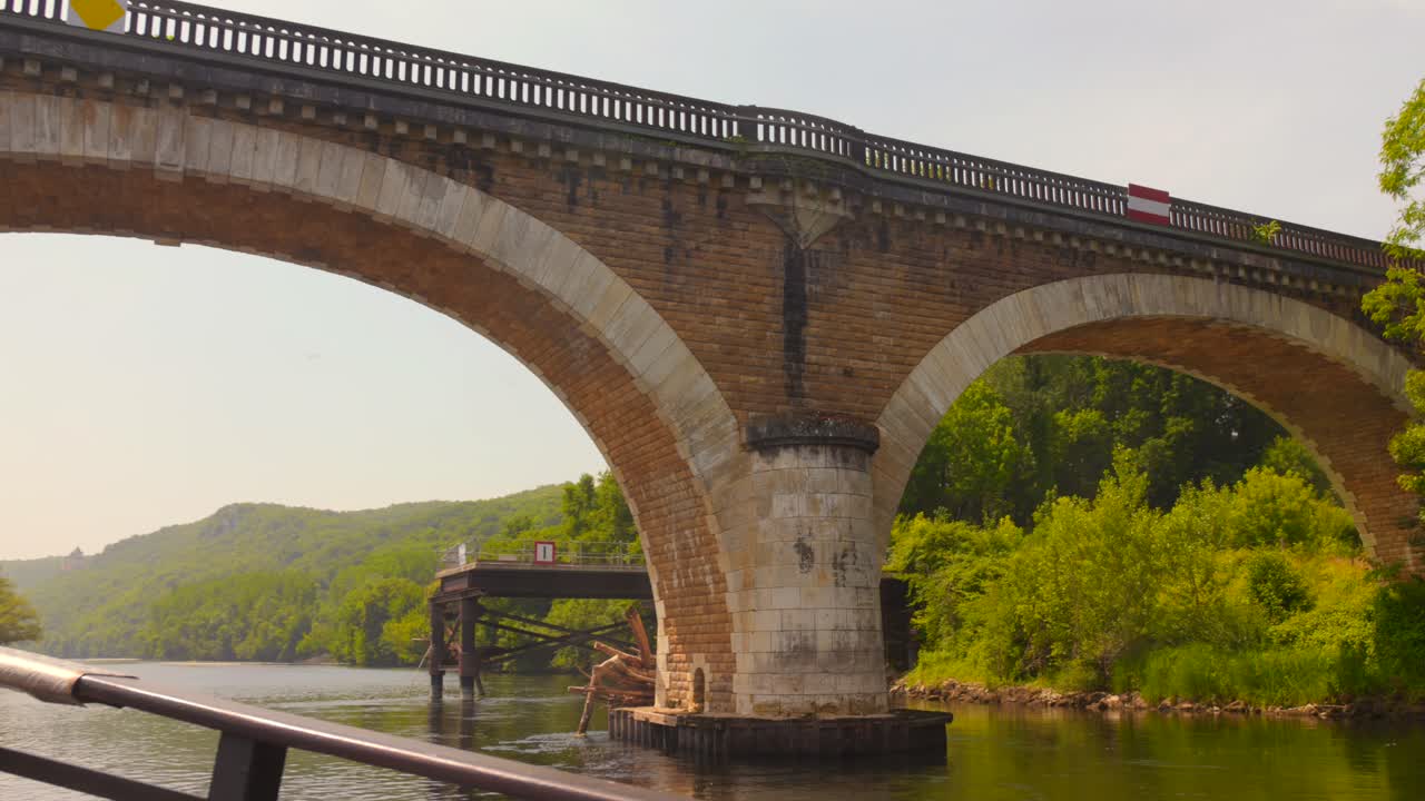 Shot of passing under stone bridge over Dordogne river, France. View from a traditional boat (gabare in French)