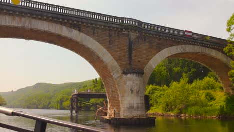shot of passing under stone bridge over dordogne river, france. view from a traditional boat (gabare in french)