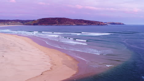 Aerial-shot-flying-out-over-the-ocean-at-sunset-with-crashing-waves