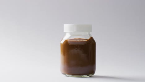 video de primer plano de un frasco de crema de chocolate sobre un fondo blanco