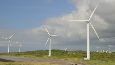 many windmills turning at windy coastal location with storm clouds