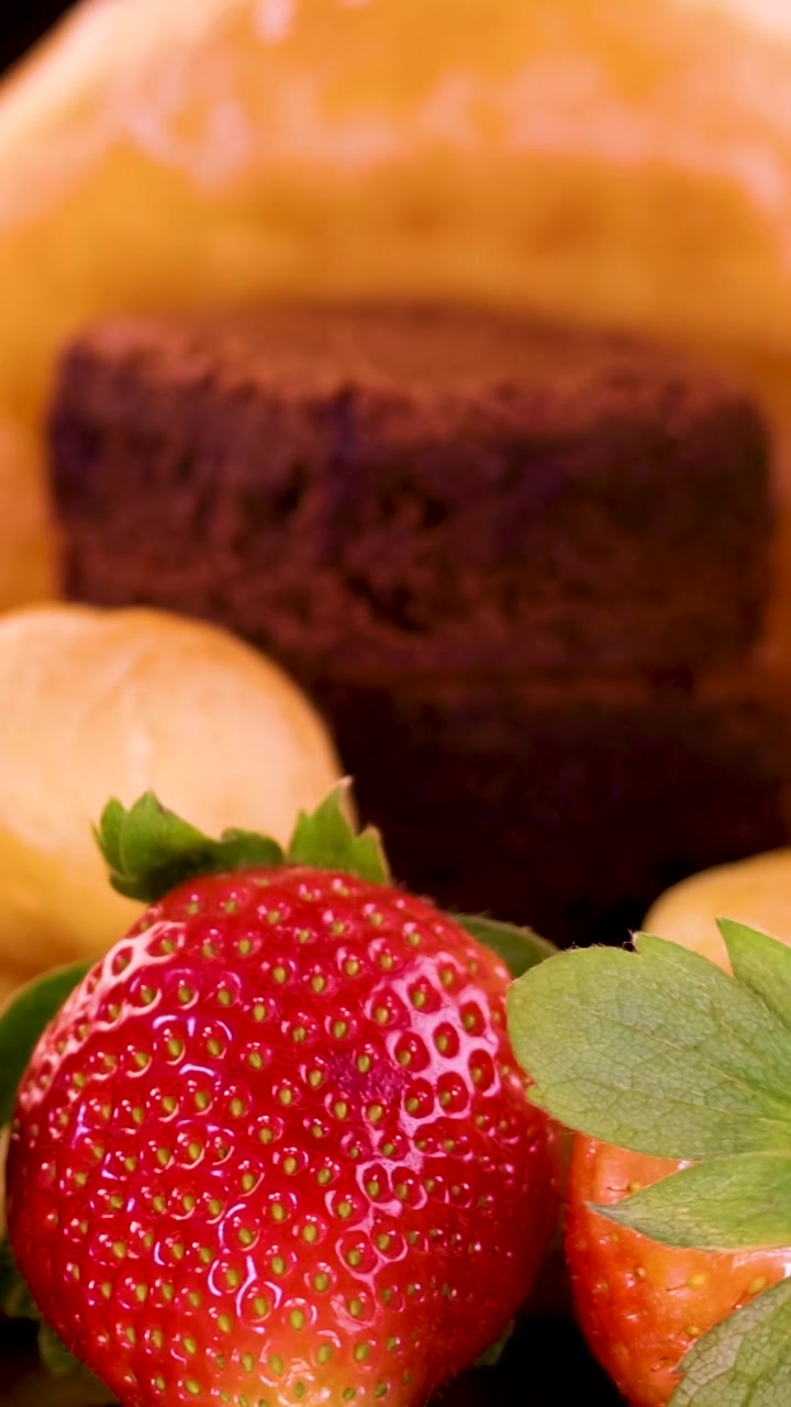 Un primo piano verticale di dessert gourmet assortiti, inclusi crostate al cioccolato e fragole fresche.