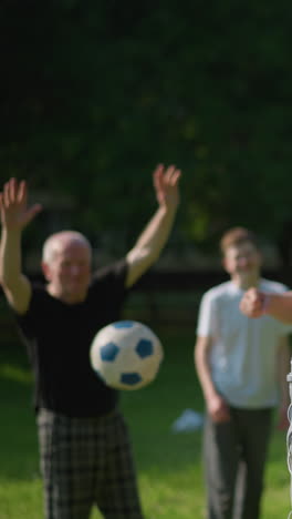 a blurred view of two people in the background while a young boy in red holds his head as a ball crosses over the net, the father playfully runs by, covering his face with his shirt playfully