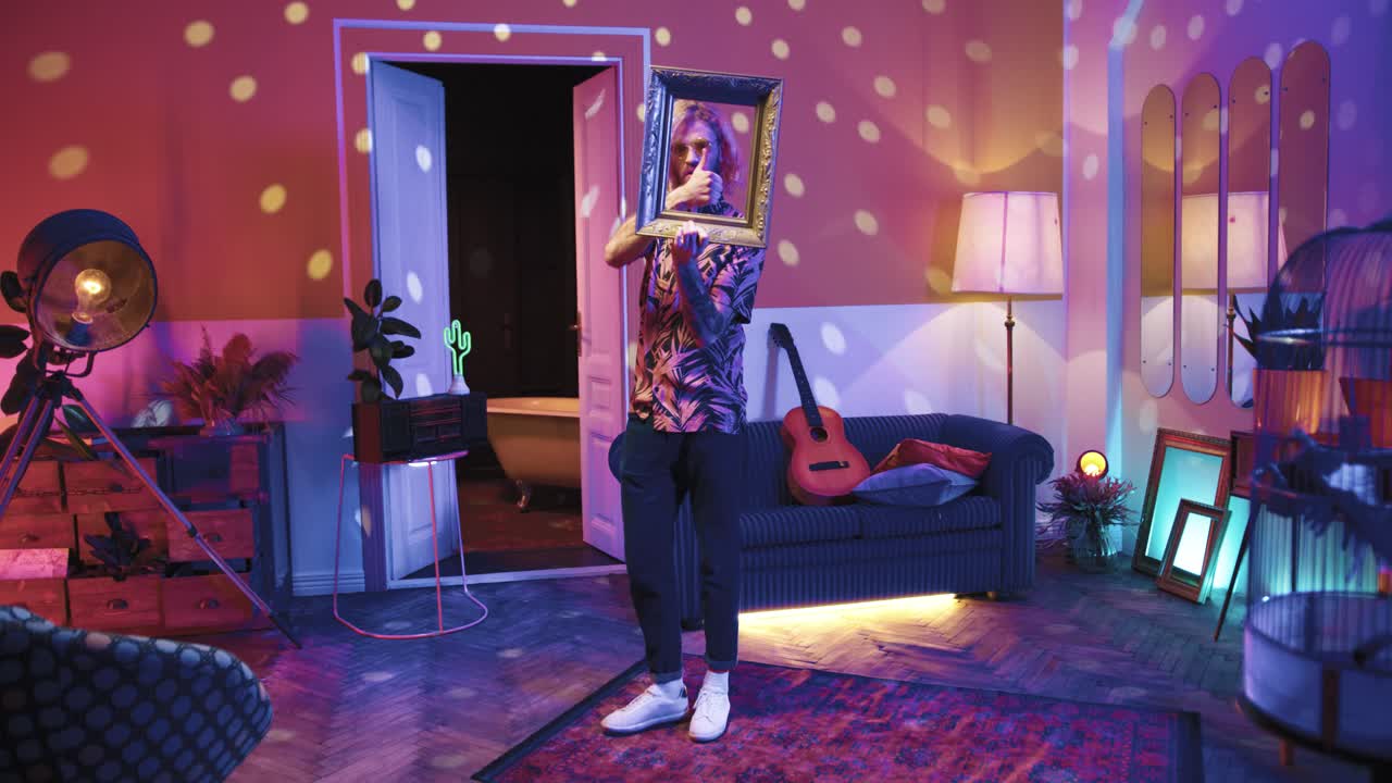 빈 프레임을 들고 집에서 복고풍 파티에서 춤을 추는 긴 머리를 가진 젊은 세련된 백인 남자