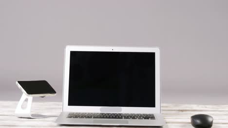 laptop, smartphone with stand and computer mouse