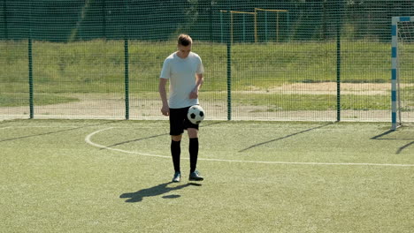 a young soccer man training freestyle tricks with the ball on a street football pitch on a sunny day 6