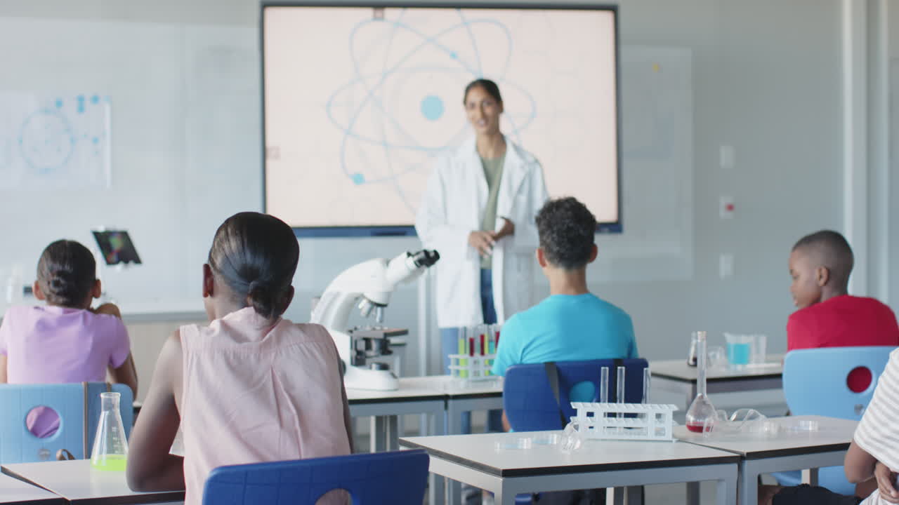 In school, teacher in lab coat explaining science to students in classroom