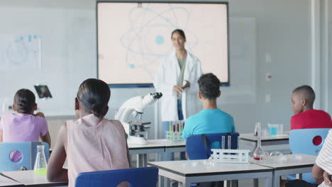 in school, teacher in lab coat explaining science to students in classroom