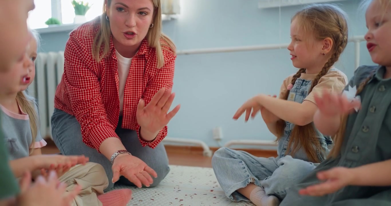 Female Teacher Leading Hand Game with Preschool Children