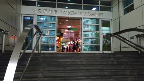 corona virus pandemic, local leaving tai kok tsui market in downtown hong kong wearing protective face masks.