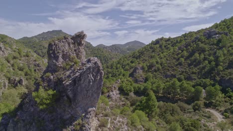 vista aérea de bajo nivel que revela picos de alta montaña, carretera y bosque mediterráneo