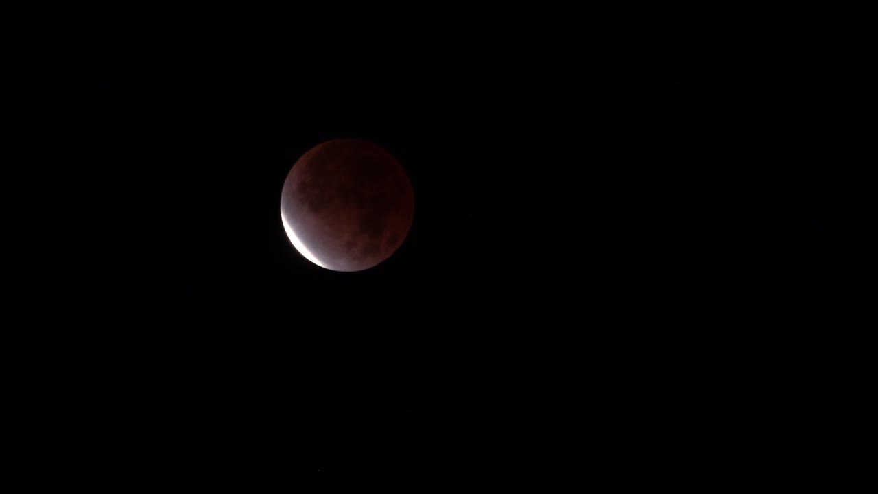 Partial Lunar Eclipse with Reddish Moon Against Dark Night Sky