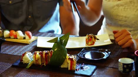 Woman-serving-sushi-on-plate-with-chopstick-in-restaurant