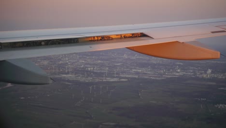 Vista-Aérea-De-La-Ciudad-Desde-Un-Avión-Con-Ala-En-Luz-Brillante-En-Primer-Plano