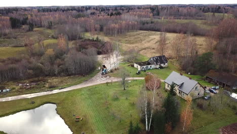 aerial footage of slowly flying over an old family home between woods in countryside of latvia