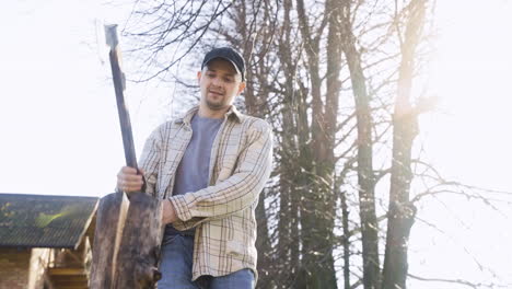 Bottom-view-of-caucasian-man-chopping-firewood-with-an-ax-outside-a-country-house