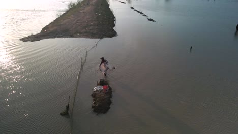 fisherman cast net fishing in tonle sap waterway in asia, aerial birds eye view during late afternoon setting sun, slow-mo