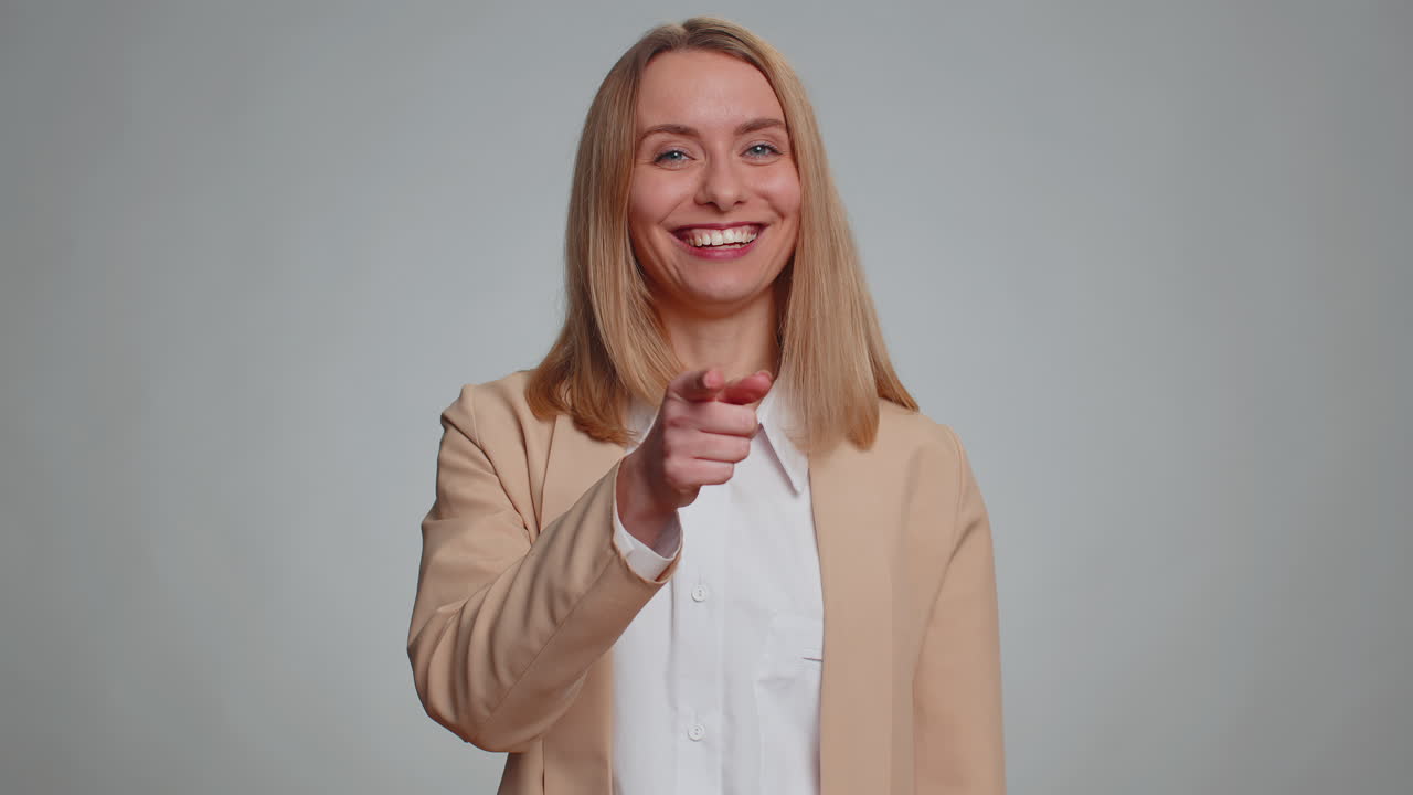 Woman pointing to camera and looking with playful happy expression making choice showing direction