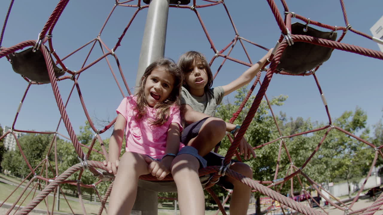 усталый брат и сестра сидят на веревочной аттракционе