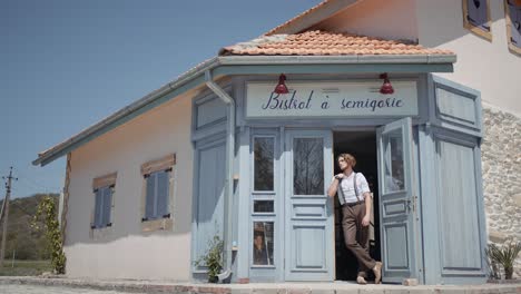 man standing outside a vintage european bistro on a sunny day