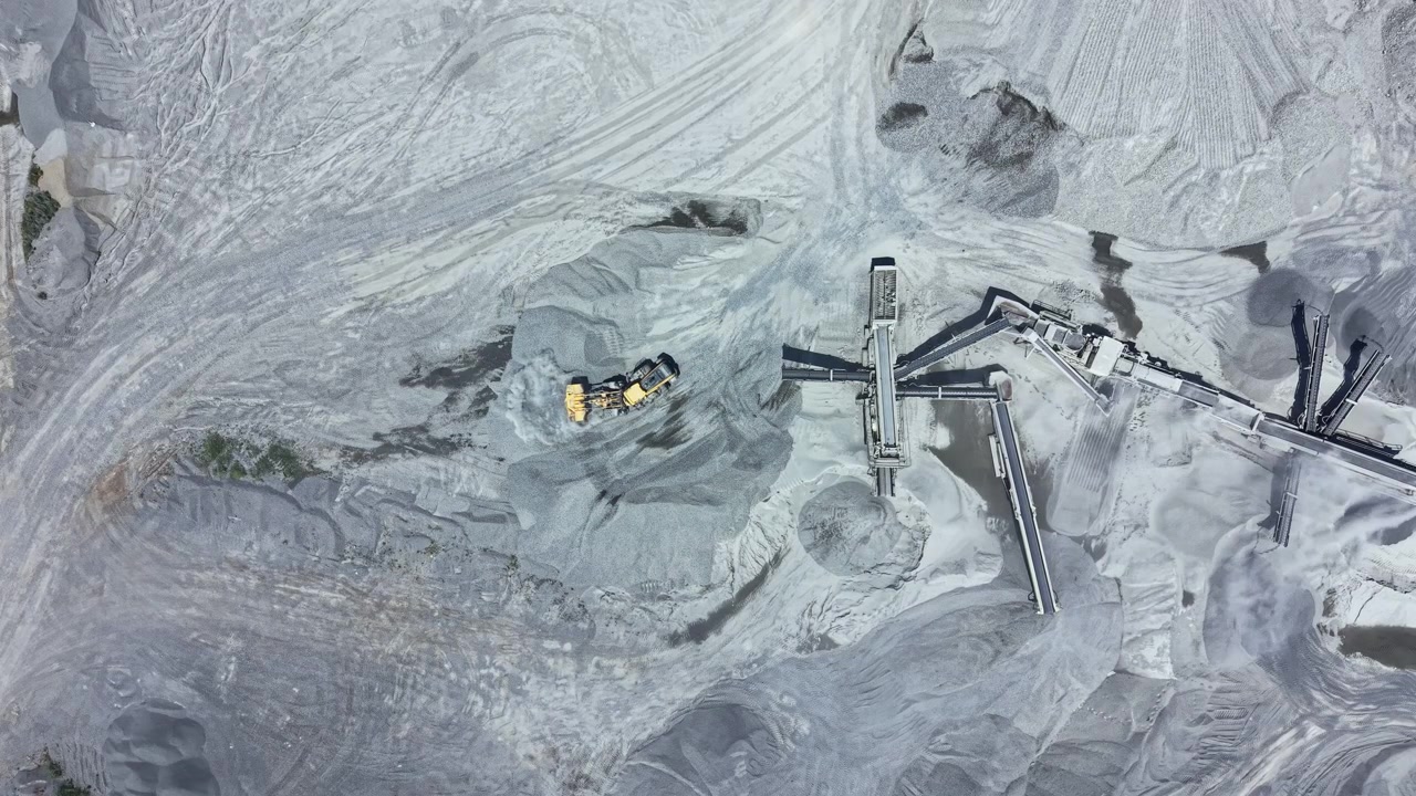 Granite quarry operation in a remote area during daylight showing equipment and rock piles