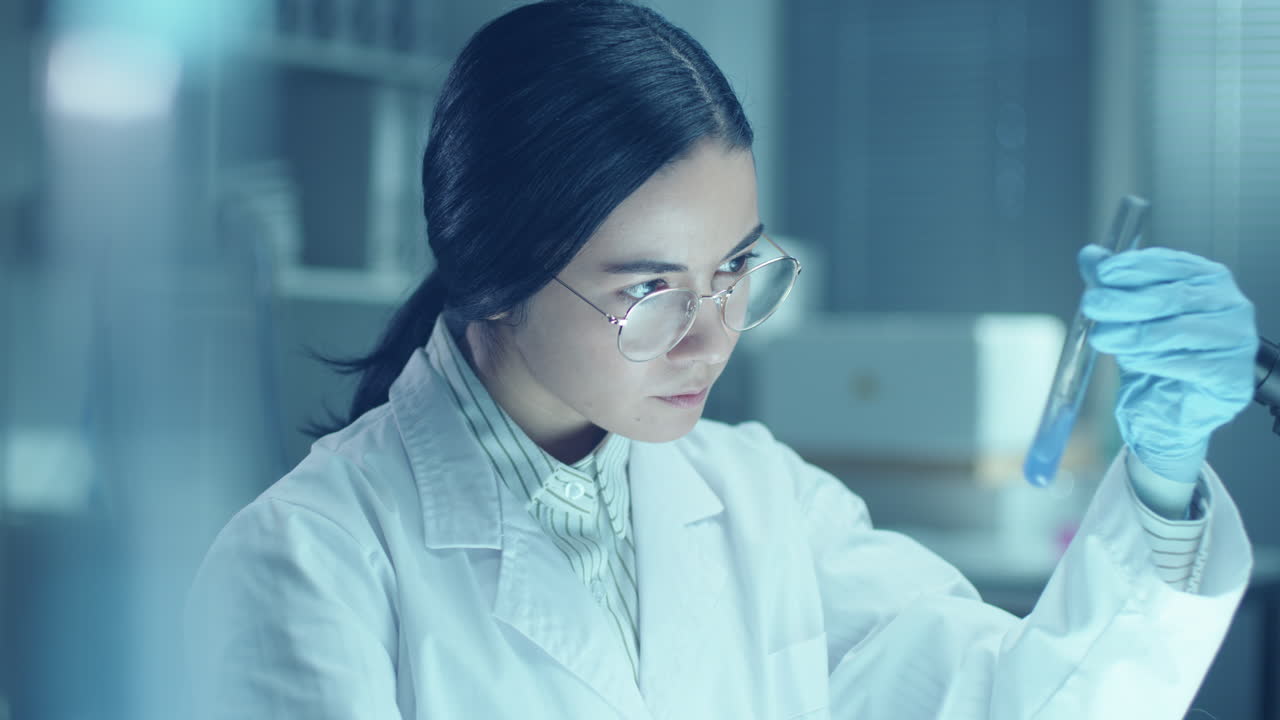 Female Chemist Mixing Liquid Substances in Test Tube during Lab Research