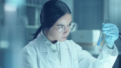 female chemist mixing liquid substances in test tube during lab research
