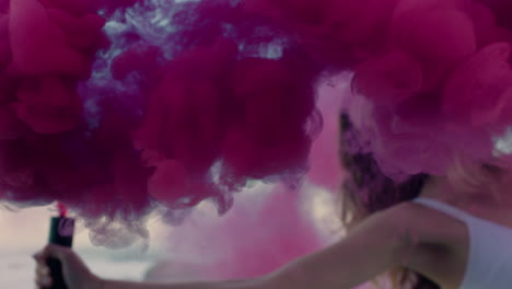 close-up-woman-holding-pink-smoke-grenade-dancing-on-beach-at-sunrise-celebrating-creative-freedom