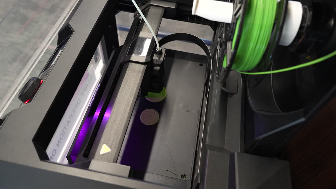 Top view shot shows the printer head and feed wire of a 3D printer at work