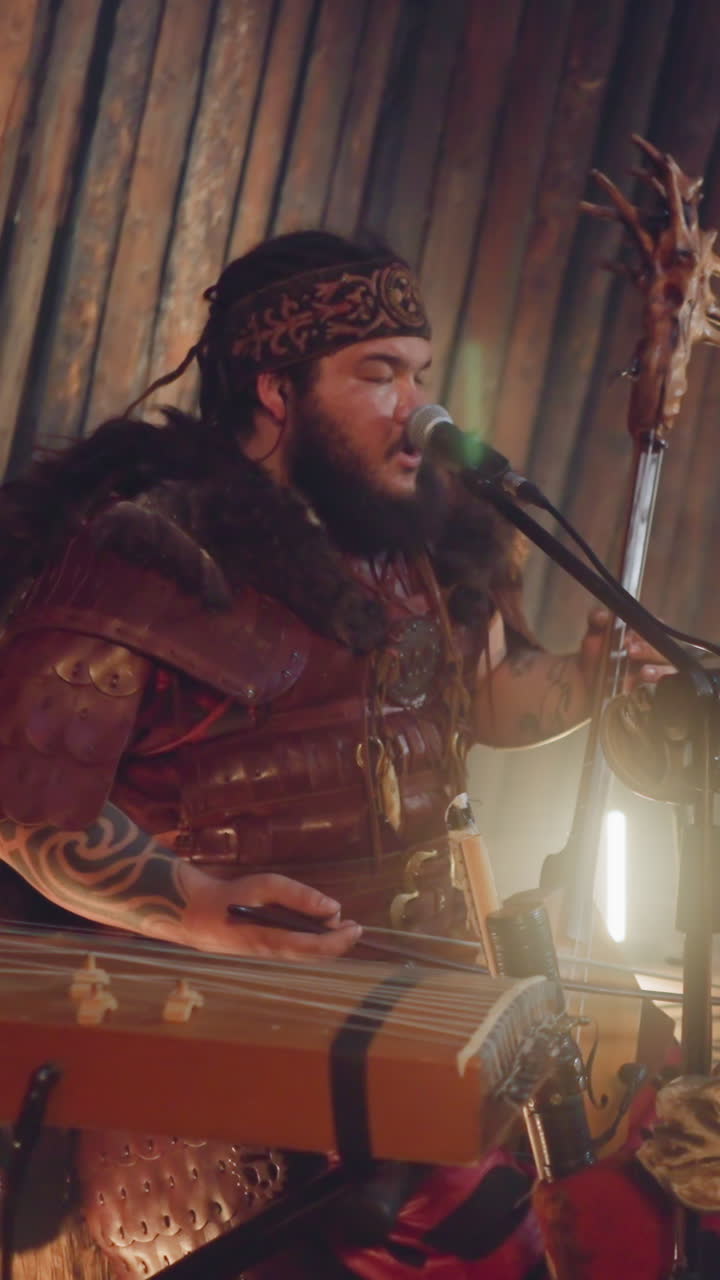 Frontman of folk rock band plays bow instrument singing by throat on stage in ail. Shamanic rituals and music show. Siberian meditative sound