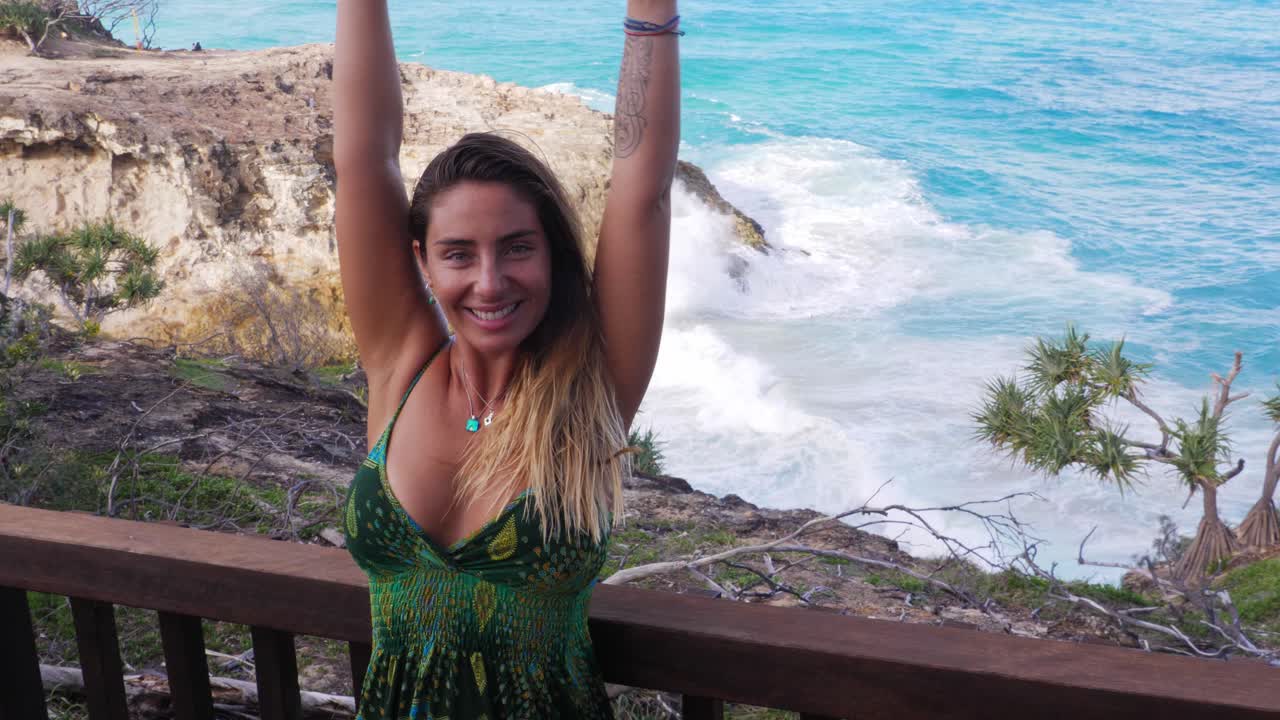 mujer feliz levantando ambas manos con olas rompiendo en el fondo - north gorge walk in point lookout, queensland, australia