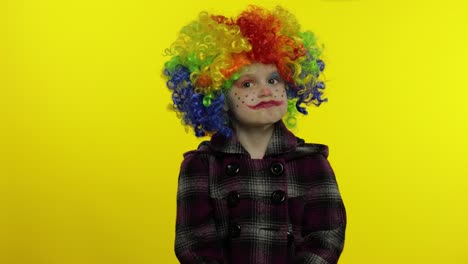 Little-caucasian-child-girl-clown-in-rainbow-wig-making-silly-faces,-hakes-her-head.-Halloween