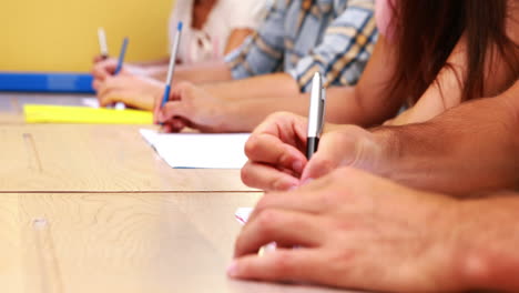 estudiantes sentados en una fila tomando notas en el aula