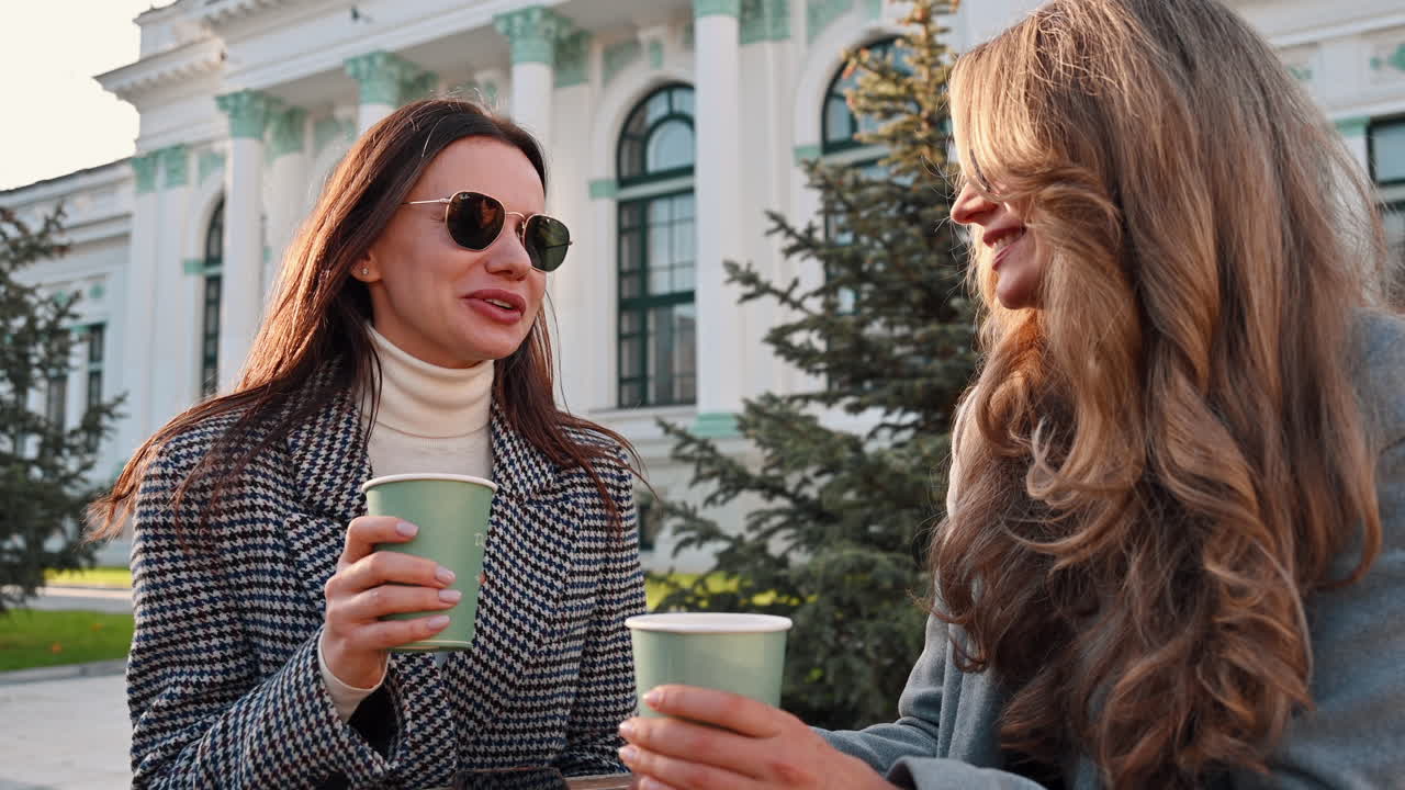 Two women talking and drinking coffee at a terrace
