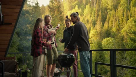 a group of friends cook food on the grill and listen to the guitar at a barbecue picnic in a country house overlooking the forest and mountains