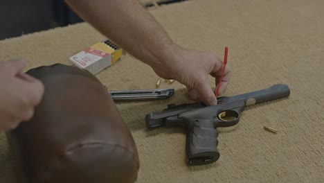 high angle view of man placing chamber view in empty handgun and indicating the pistol is clear