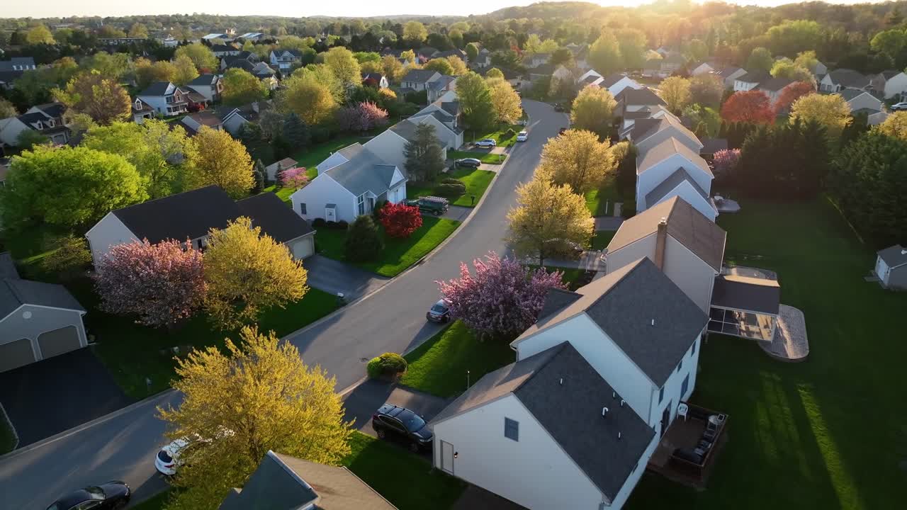 Lingkungan Amerika modern dengan label 'terjual' animasi di atas atap. Pemandangan udara pasar perumahan yang mahal dan populer. Matahari terbenam 'golden hour' selama musim semi