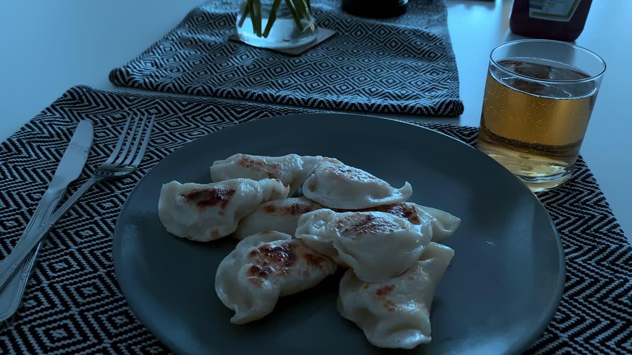Dolly, dumplings for white plates placed on the table, next to it stands a glass with a sparkling beverage