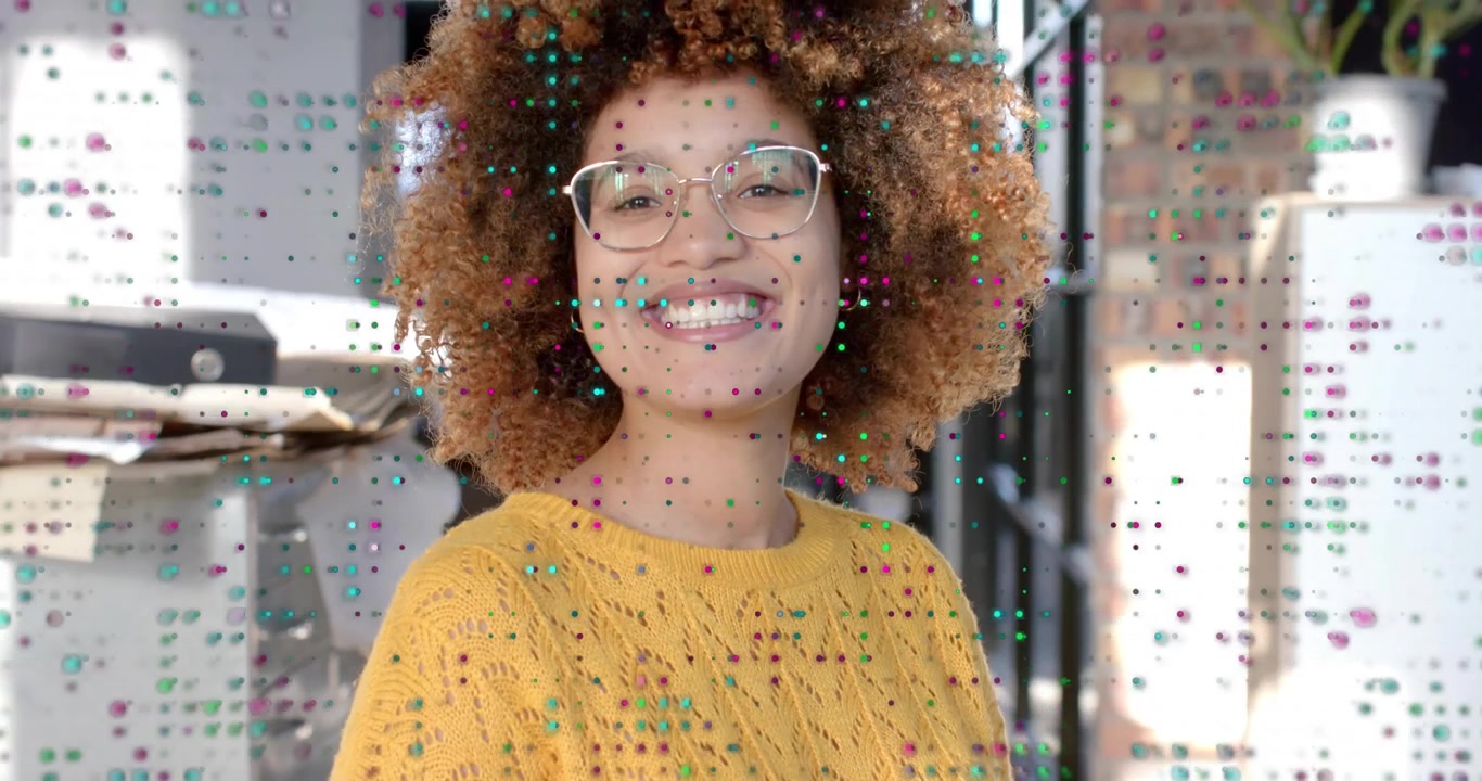 Donna che reagisce a una sovrapposizione di pixel in uno studio di design, girando il busto e allargando il sorriso.