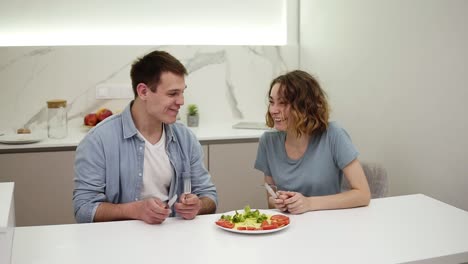 joven pareja familiar disfrutando del desayuno juntos comiendo tortilla de un solo plato, rutina diaria novia amor relación de cuidado sentado en la mesa del bar junto con el guapo novio