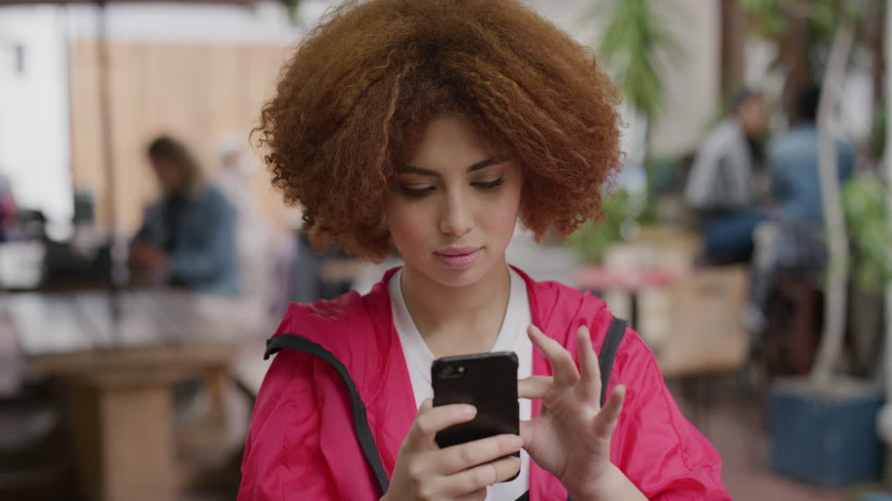 portrait of young mixed race woman using smartphone texting browsing mobile phone messaging in vibrant urban background people restuarant