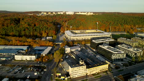 factory buildings and football stadium in front of the colorful forest in gdynia city, poland