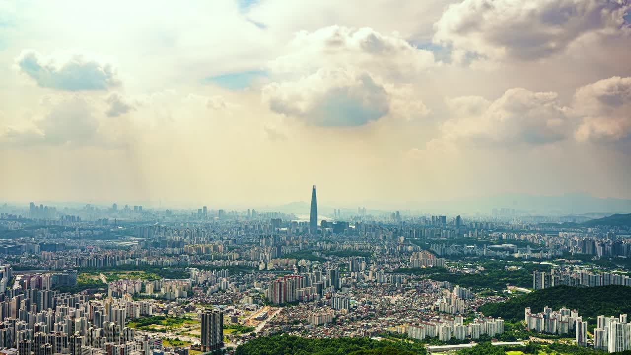 Beams of sunlight break through moody clouds to illuminate the massive cityscape of Seoul, South Korea, with the iconic Lotte World Tower serving as the central focal point.
