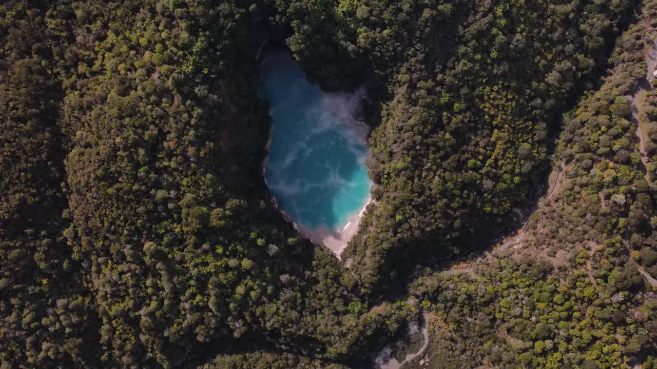 vista aérea hacia abajo surgiendo de un lago de cráter volcánico turquesa rodeado de bosque tropical