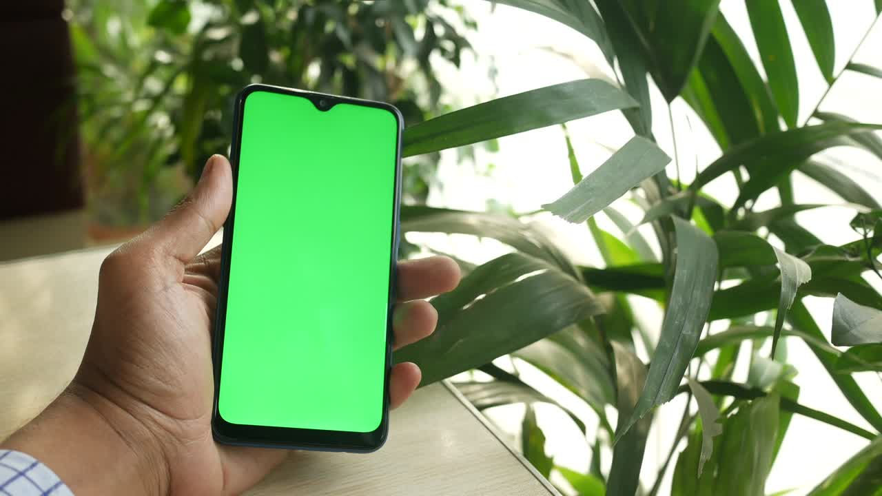 close up de la mano de un joven usando un teléfono inteligente con pantalla verde