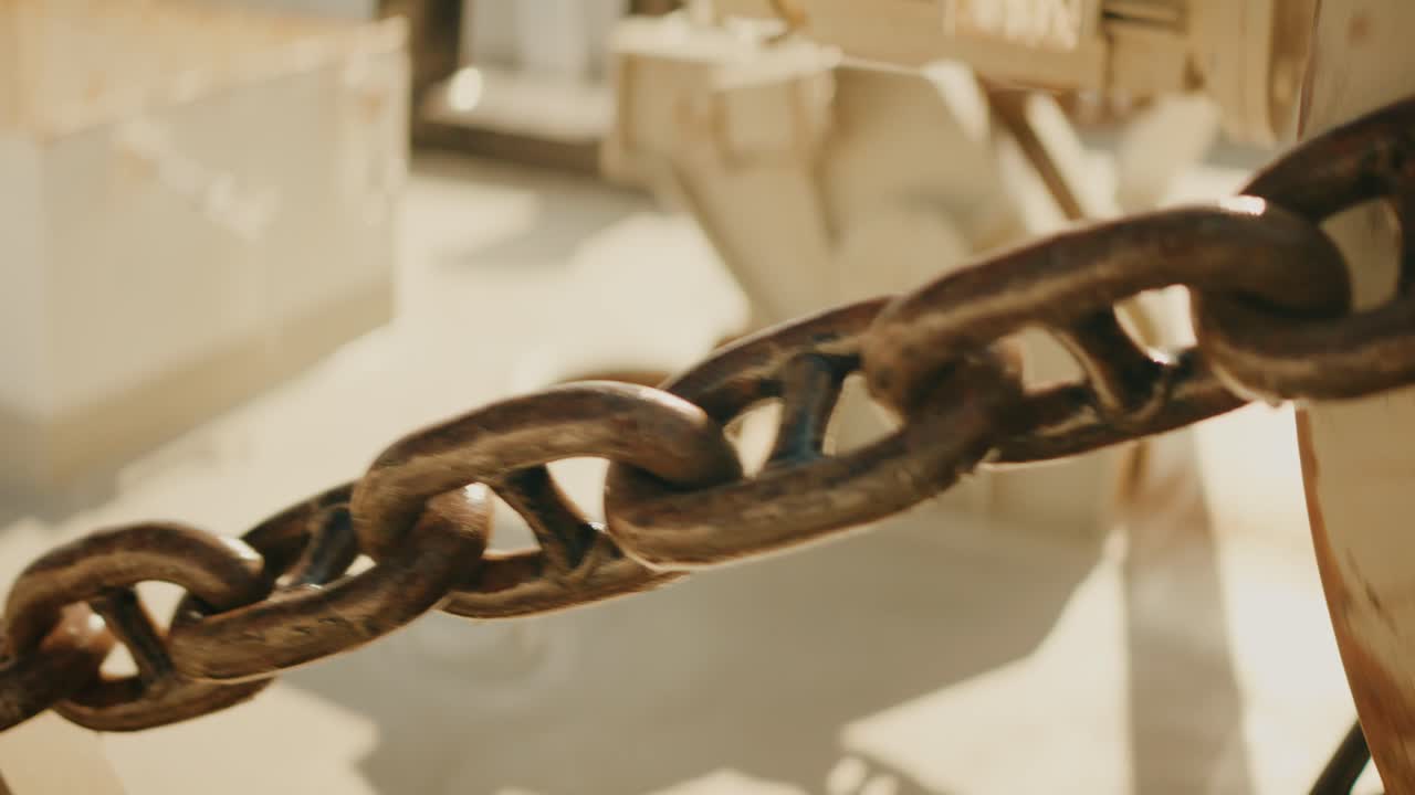 Primer plano de una cadena de ancla siendo izada en la cubierta de un barco bajo la cálida luz del sol.