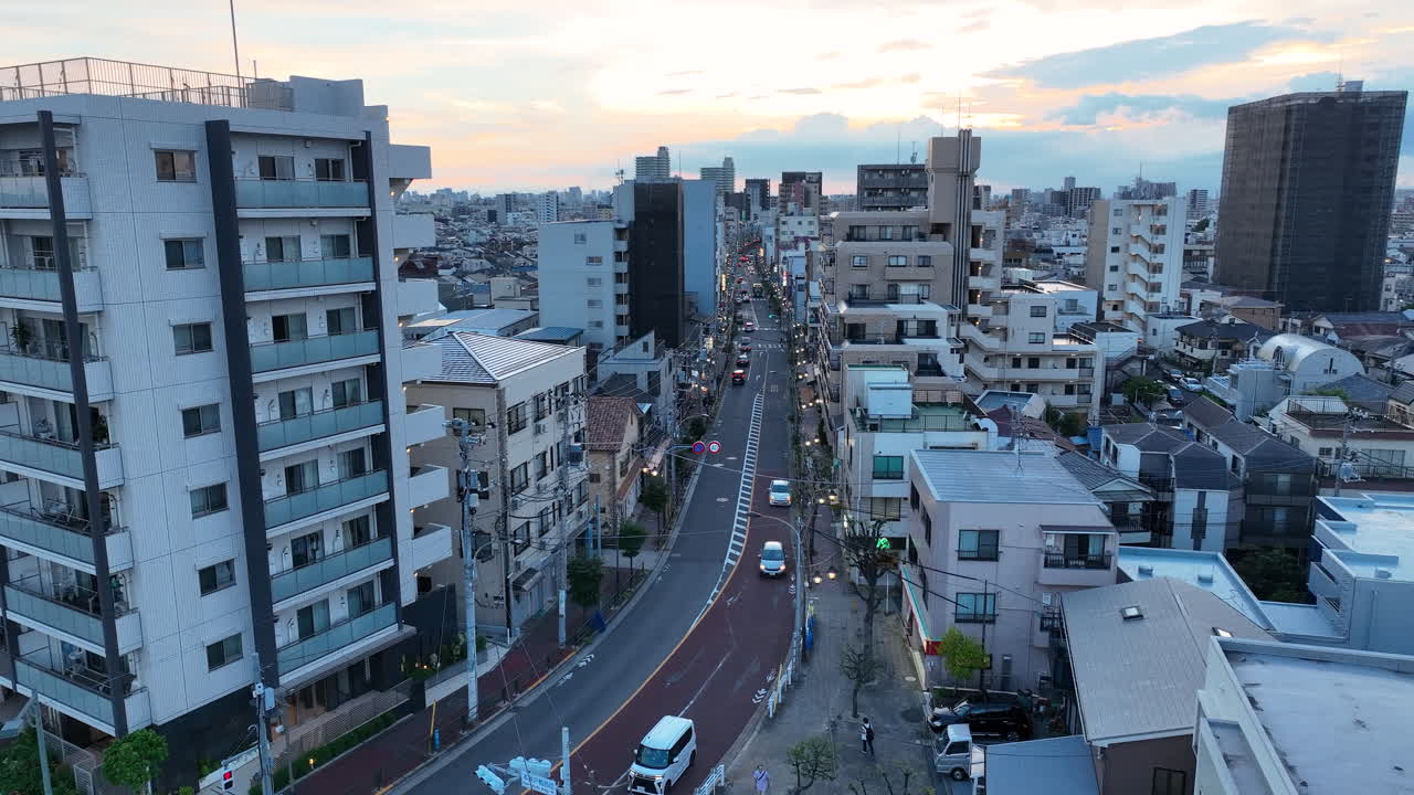 Few Cars Driving In The Street Along The Buildings At Dusk In Kyoto, Japan. - aerial shot