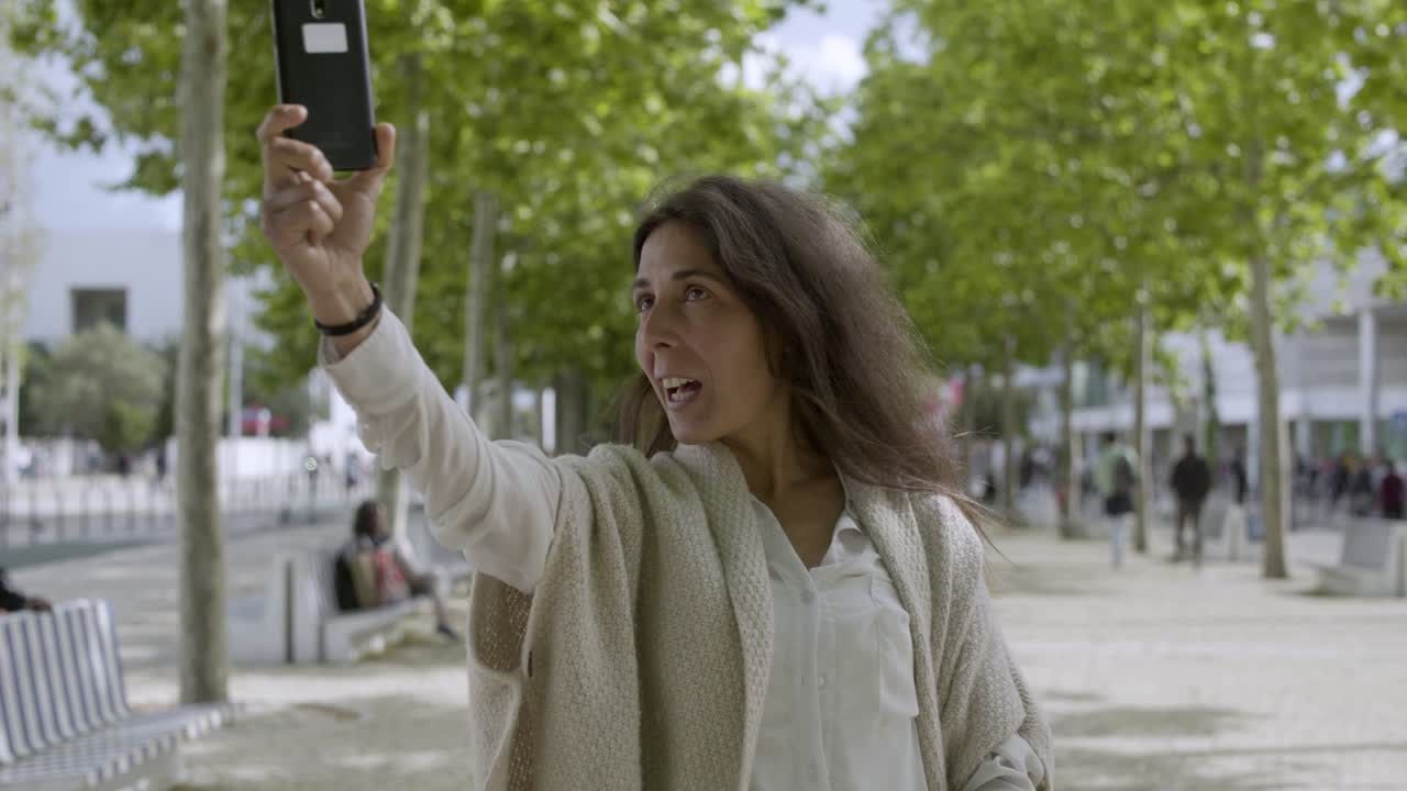 Mulher de meia-idade alegre gravando vídeo com smartphone