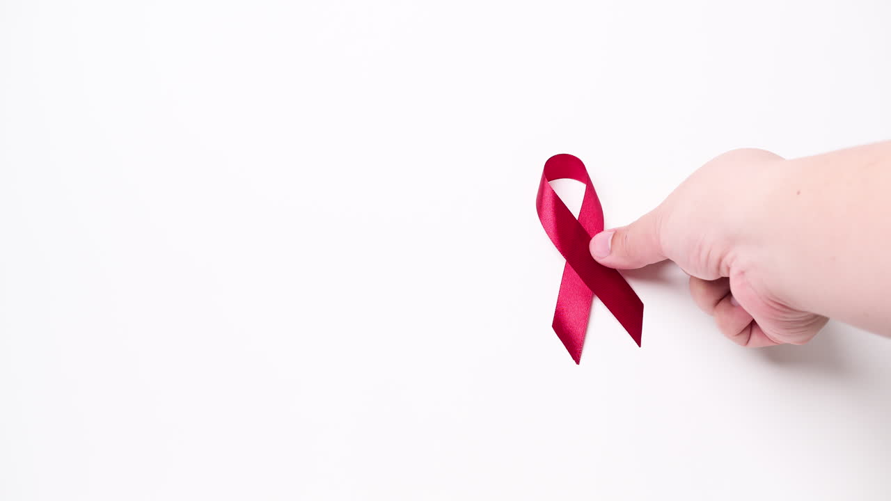 detalle de la mano masculina poniendo cinta en color rojo sobre fondo blanco